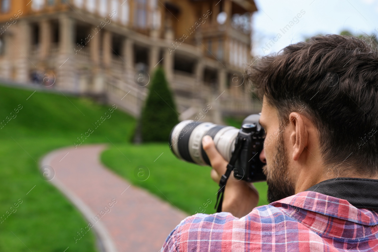 Photo of Photographer taking photo of beautiful house with professional camera outdoors