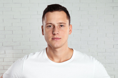 Handsome young man near white brick wall