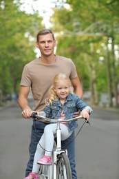 Man and his little daughter with bicycle on street