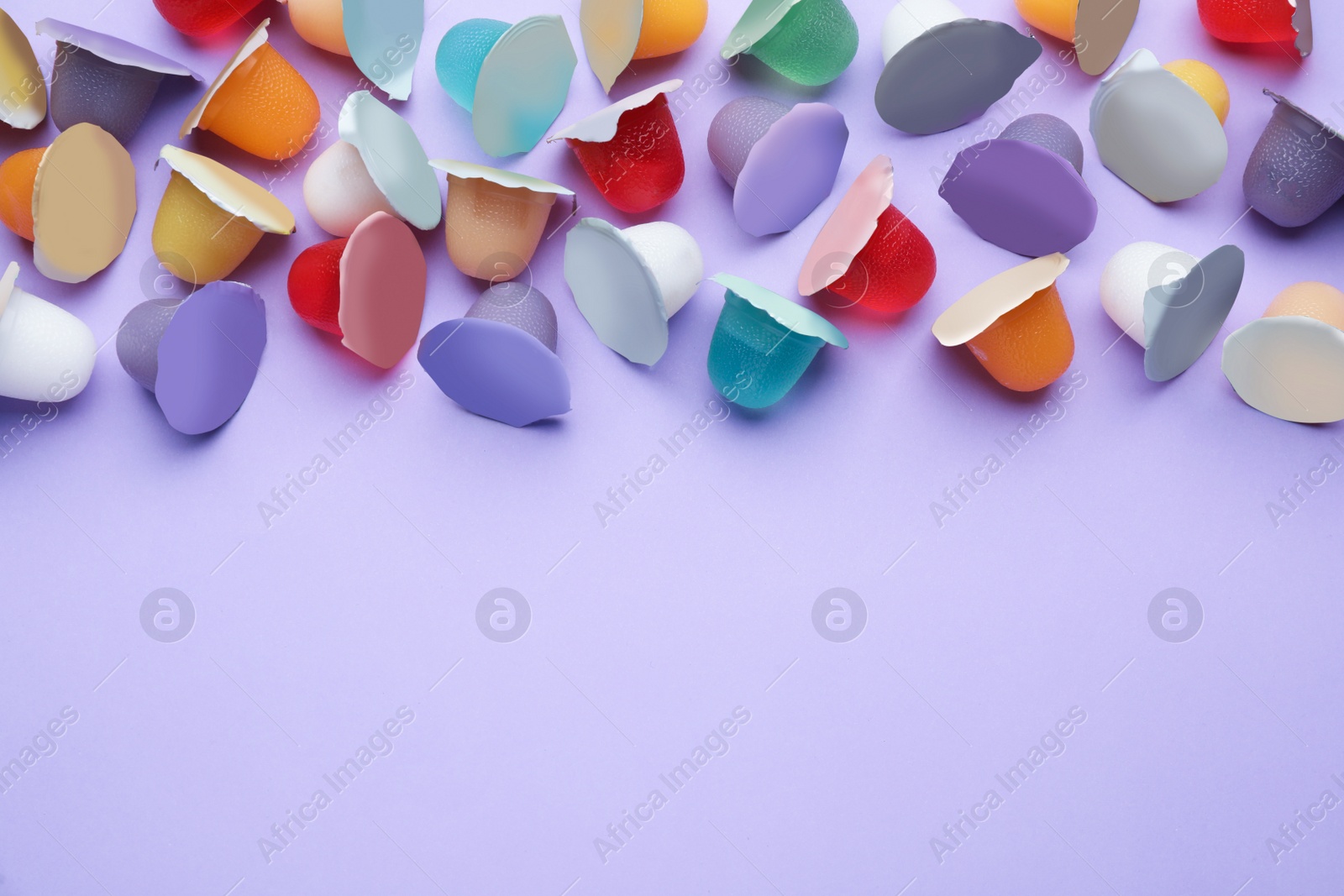 Photo of Tasty bright jelly cups on violet background, flat lay. Space for text