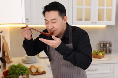 Man tasting dish after cooking in kitchen