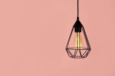 Modern hanging lamp on color background, space for text. Idea for interior design