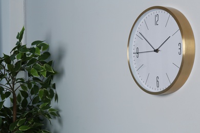 Photo of Stylish clock on wall indoors. Time management