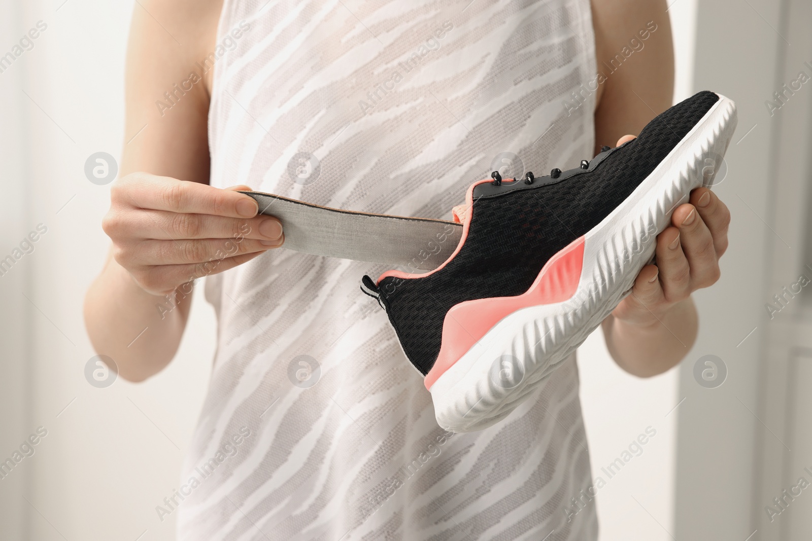 Photo of Woman putting orthopedic insole into shoe indoors, closeup. Foot care