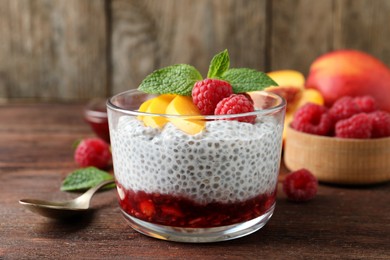 Photo of Delicious chia pudding with raspberries, peach and mint on wooden table
