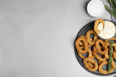 Photo of Fried onion rings served on grey table, flat lay. Space for text