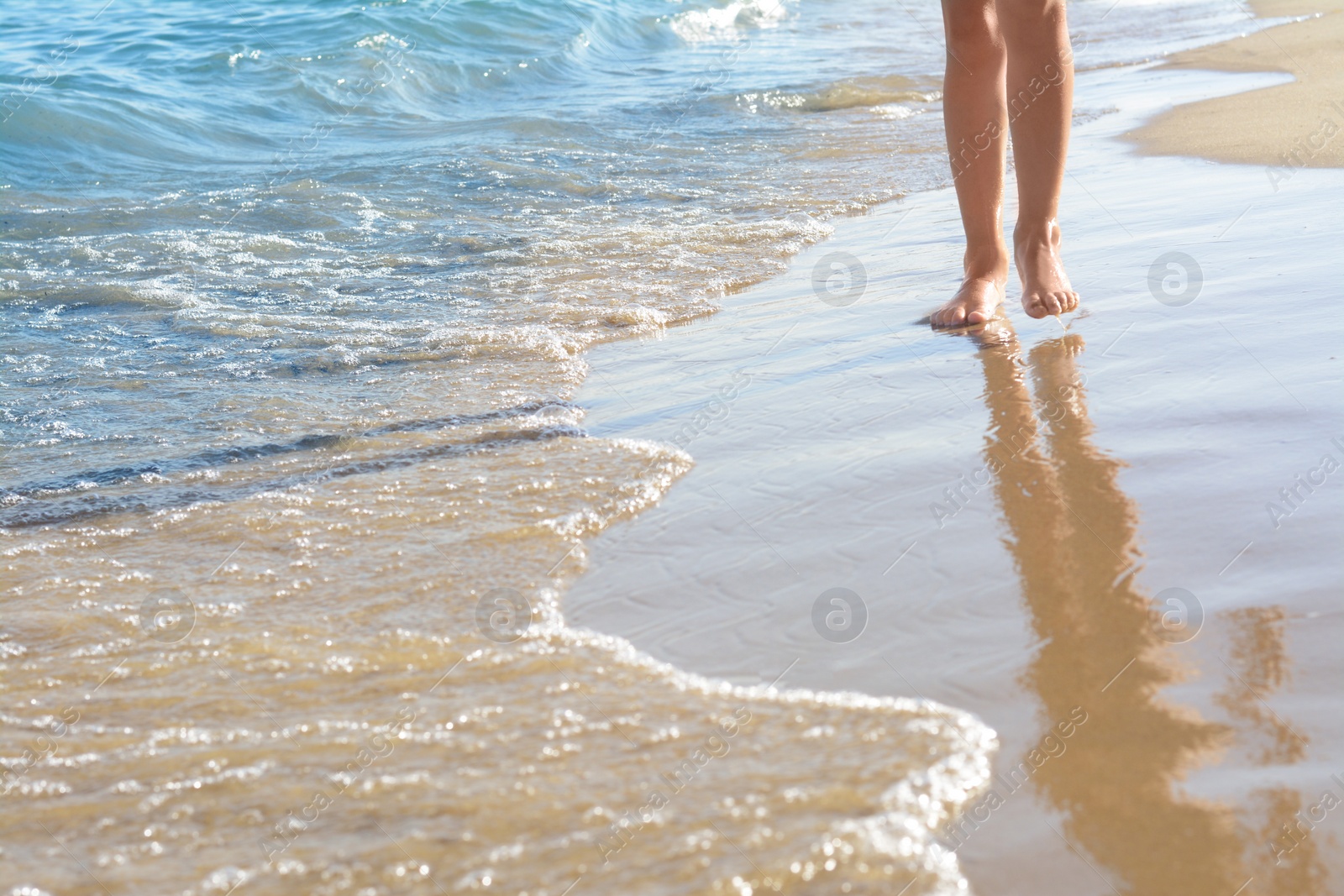 Photo of Woman walking on sandy beach near sea, closeup. Space for text