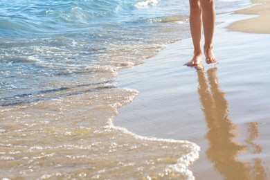 Photo of Woman walking on sandy beach near sea, closeup. Space for text
