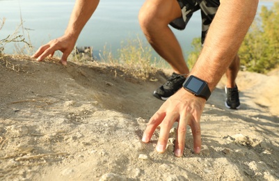 Photo of Man wearing modern smart watch during training outdoors, closeup