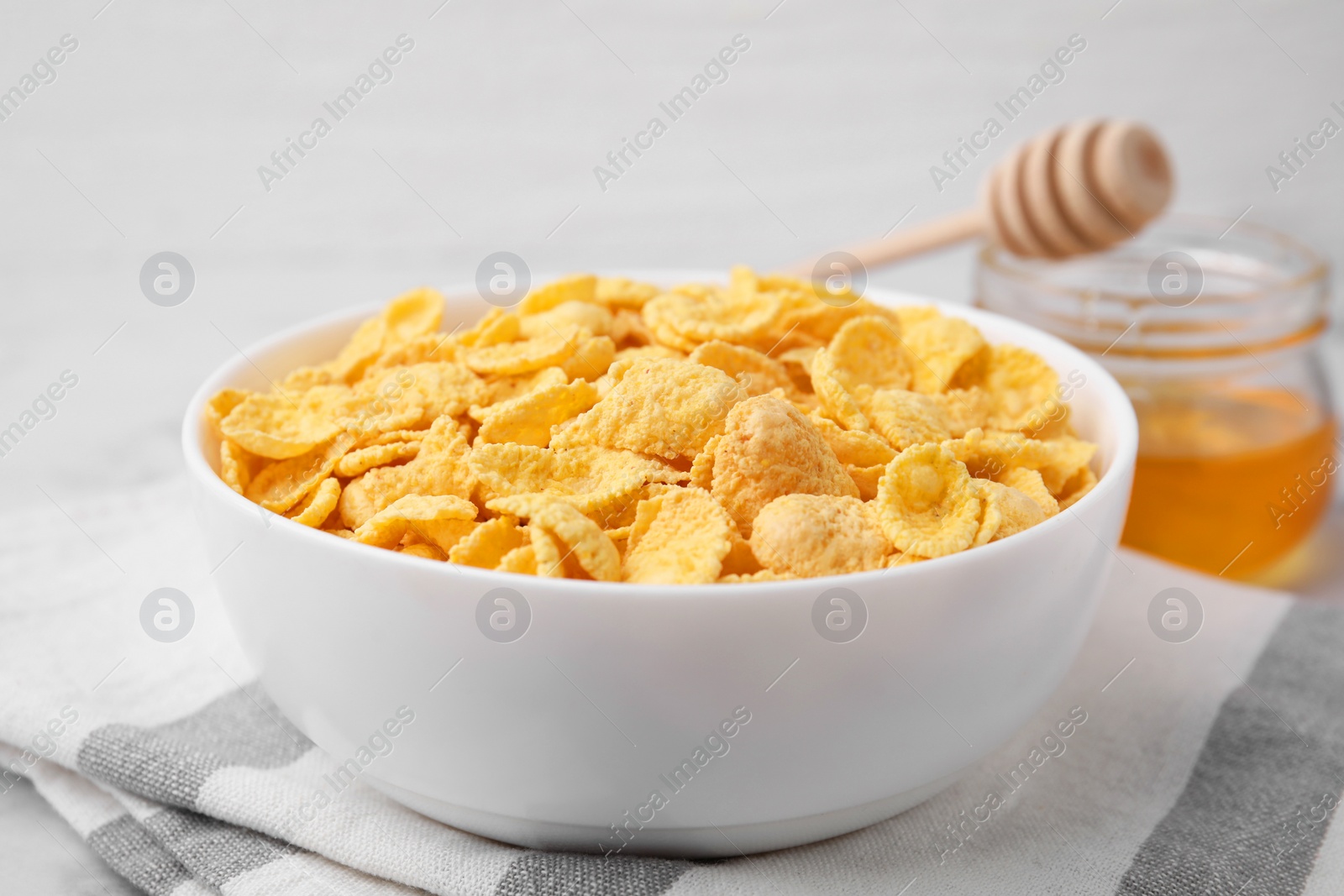 Photo of Tasty crispy corn flakes in bowl on table, closeup. Breakfast cereal