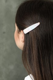 Photo of Young woman with beautiful hair clip on grey background, closeup