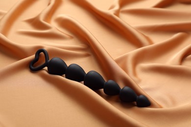Photo of Black anal ball beads on golden silk fabric. Sex toy
