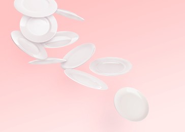 Image of Many white plates falling on pastel pink background