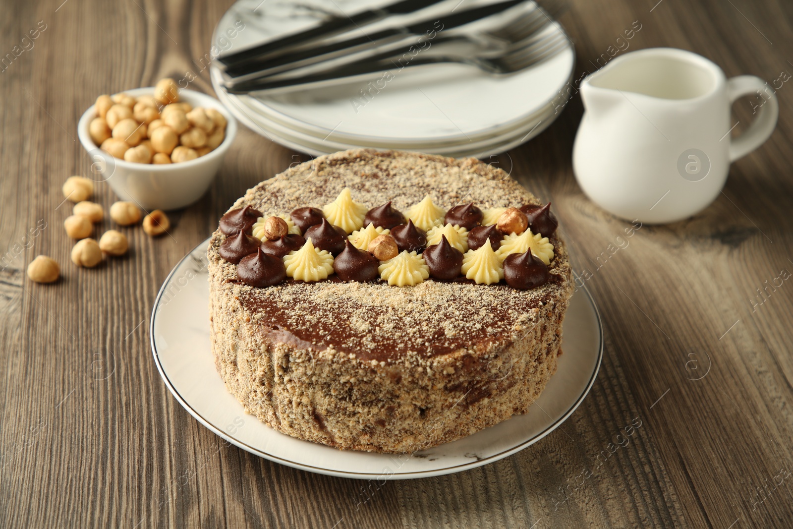 Photo of Delicious Kyiv Cake with cream and hazelnuts served on wooden table