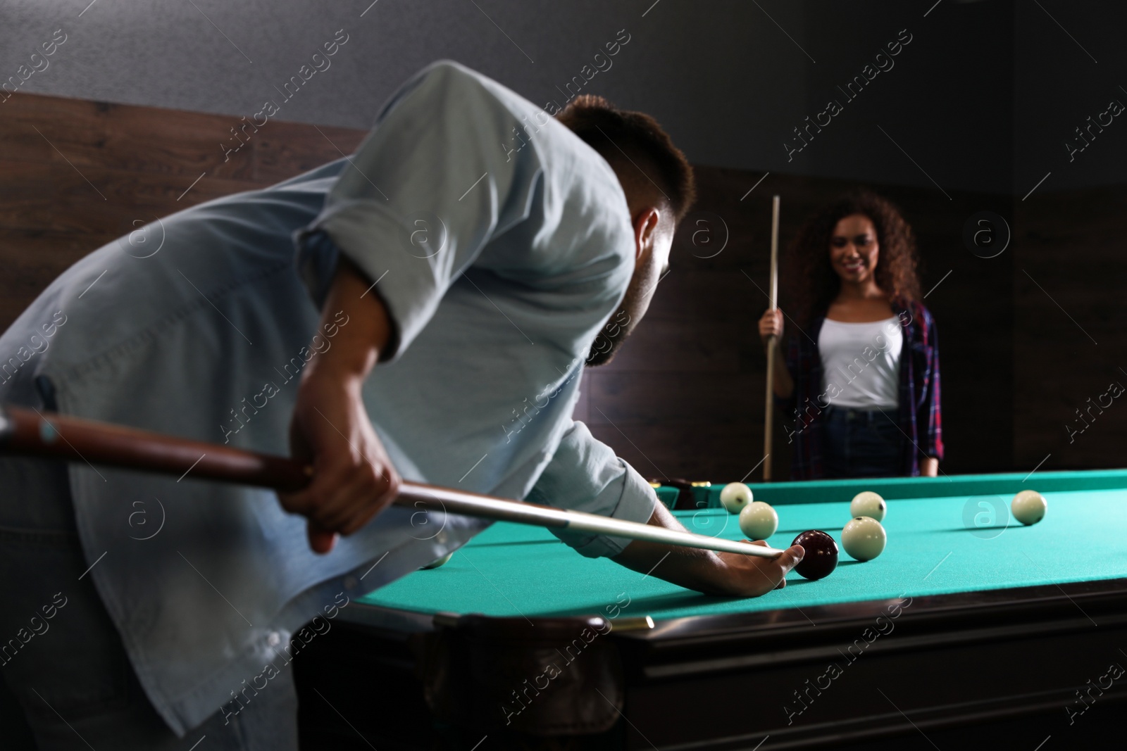 Photo of Young man and woman playing billiard indoors