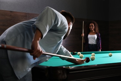 Photo of Young man and woman playing billiard indoors