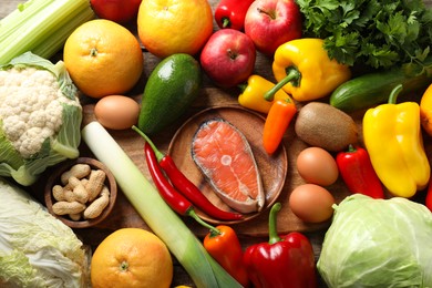 Photo of Healthy meal. Different vegetables and raw salmon on wooden table, flat lay