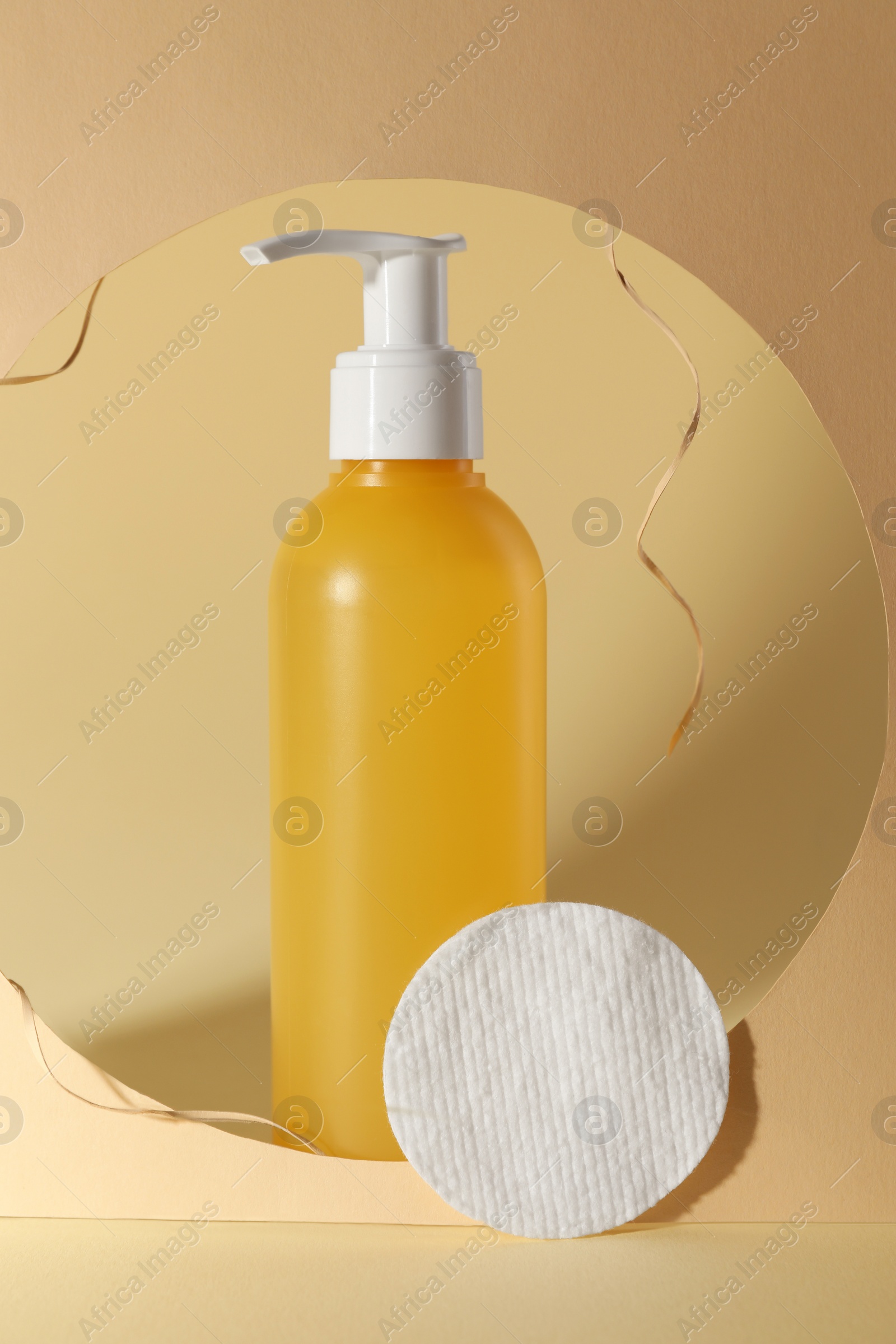 Photo of Hole with face cleansing product and cotton pad on beige background