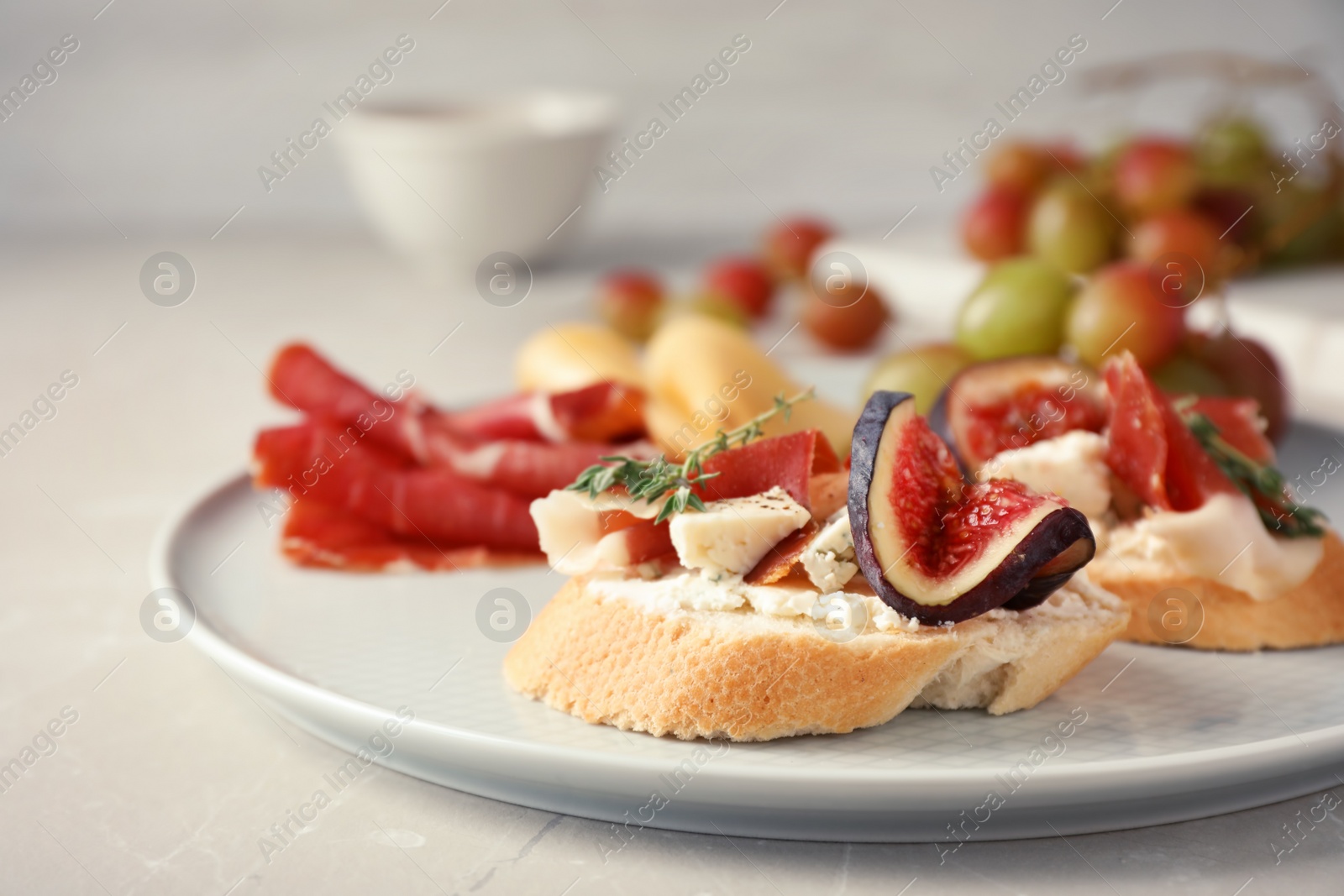 Photo of Sandwich with ripe fig, prosciutto and cheese on plate, closeup