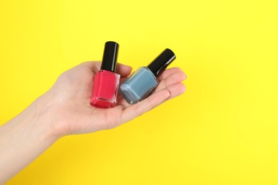 Photo of Woman holding nail polishes on yellow background, closeup