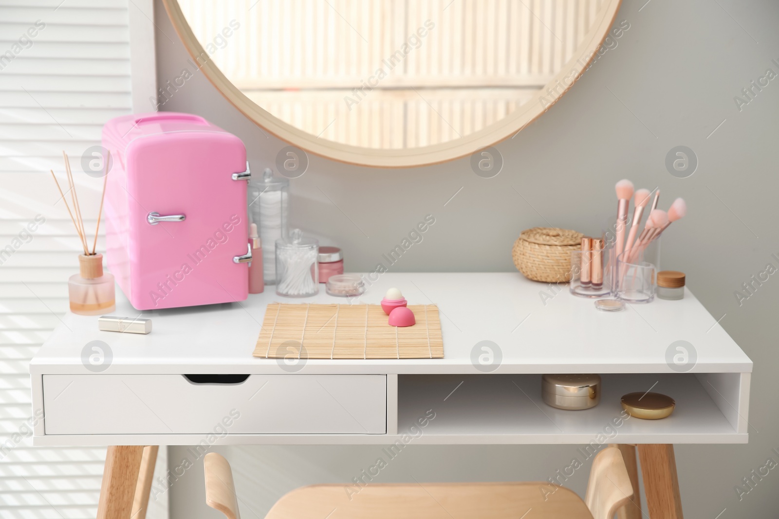 Photo of Cosmetics refrigerator and skin care products on white vanity table indoors