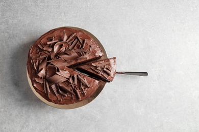 Photo of Tasty homemade chocolate cake and shovel with piece on table, top view. Space for text