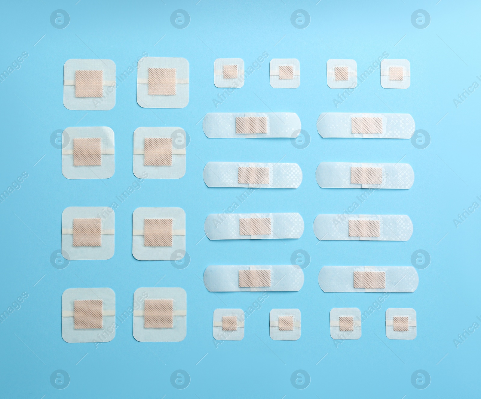 Photo of Different types of sticking plasters on light blue background, flat lay