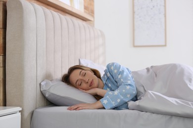 Photo of Young woman sleeping in comfortable bed with silky linens