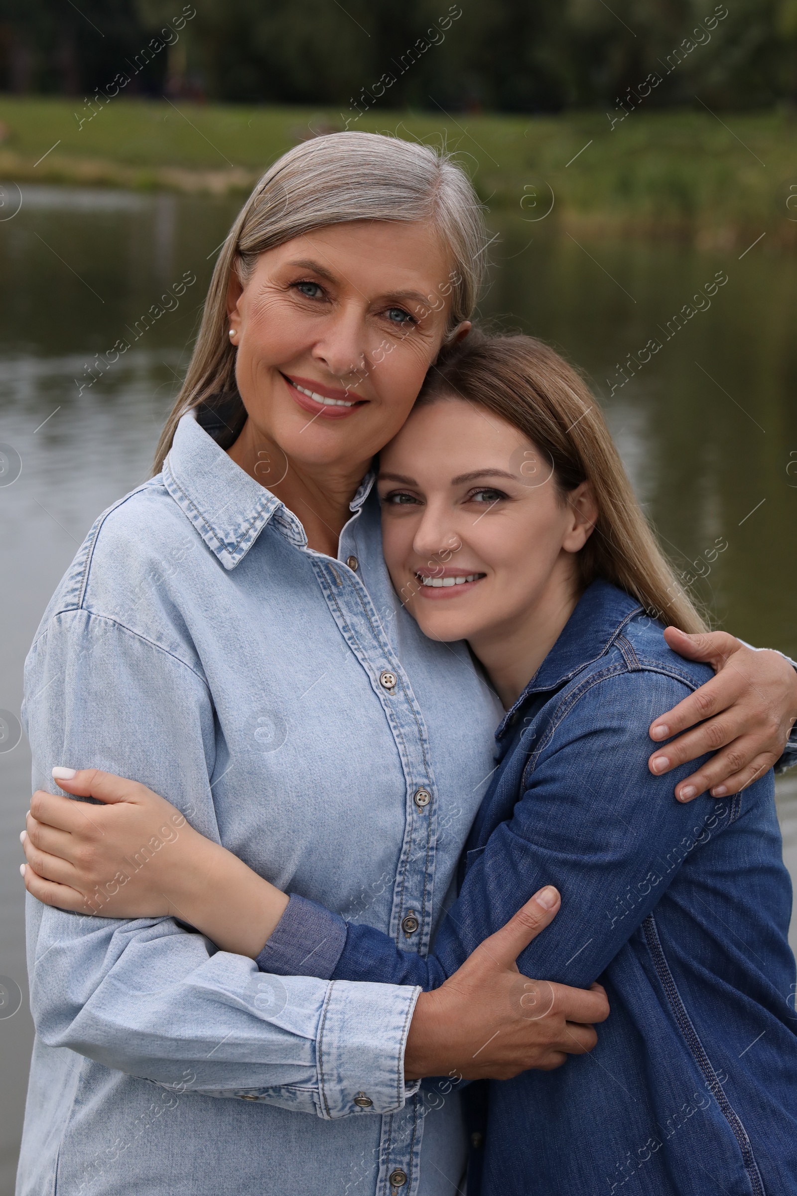 Photo of Happy mature mother and her daughter near pond