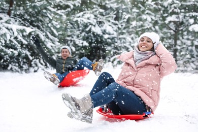 Happy couple sledding outdoors on winter day. Christmas vacation