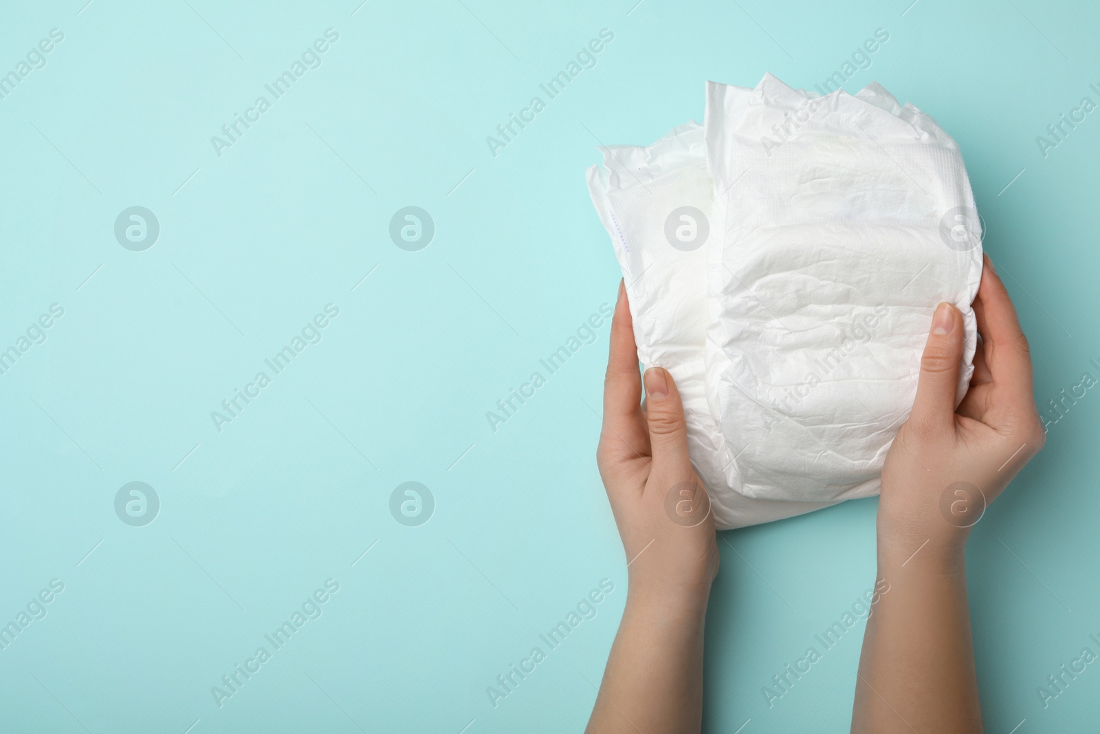 Photo of Woman with diapers on turquoise background, closeup. Space for text