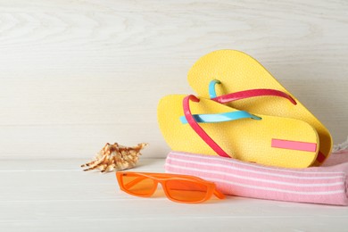 Photo of Stylish flip flops and beach accessories near white wooden wall