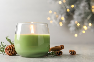 Composition with burning candle and pinecone on light grey table, space for text