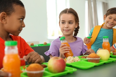 Photo of Children sitting at table and eating healthy food during break at school