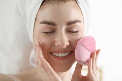 Photo of Washing face. Young woman with cleansing brush on light background, closeup