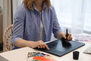 Photo of Professional designer with graphic tablet at table indoors, closeup