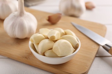 Photo of Fresh garlic and knife on white wooden table, closeup