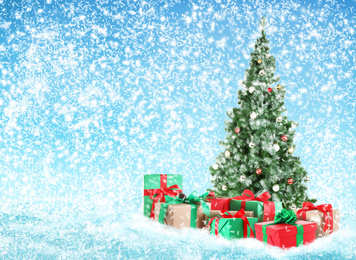 Image of Beautiful Christmas tree with gifts under snowfall, space for text