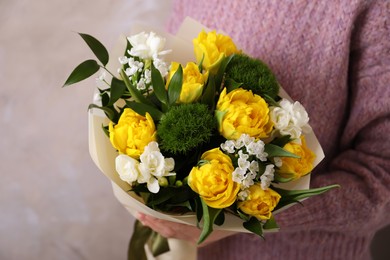 Woman with bouquet of beautiful tulips on beige background