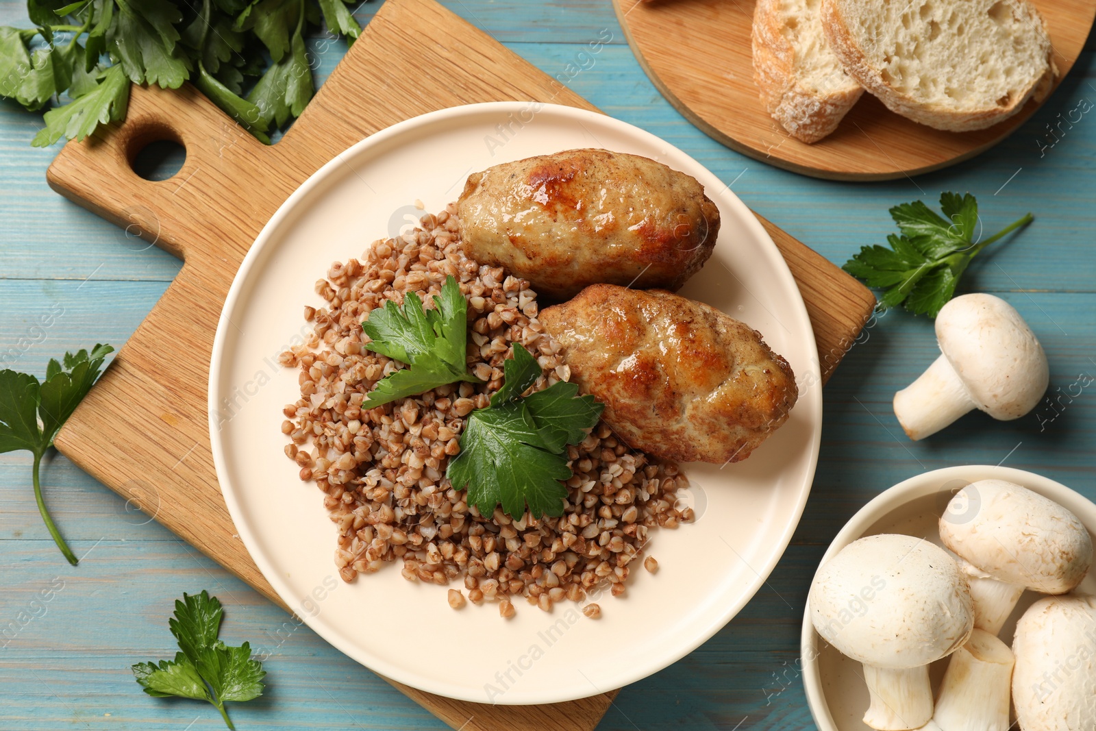 Photo of Tasty buckwheat with fresh parsley and cutlets on light blue wooden table, flat lay