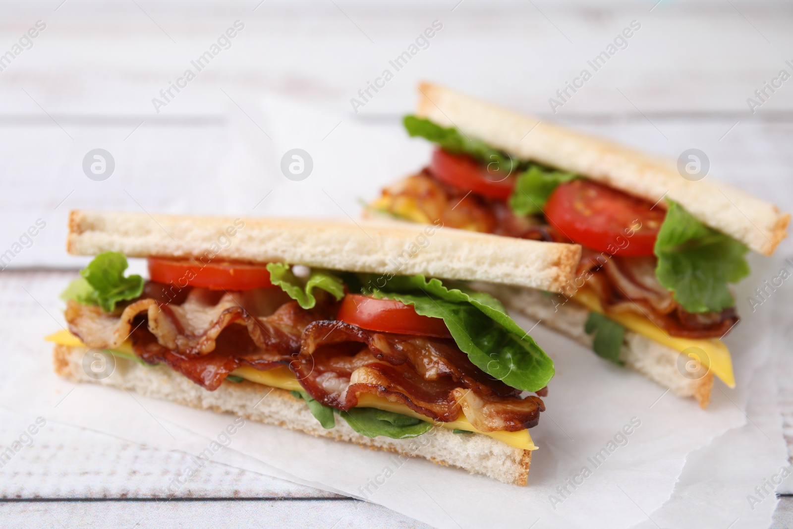 Photo of Delicious sandwiches with fried bacon on wooden rustic table, closeup