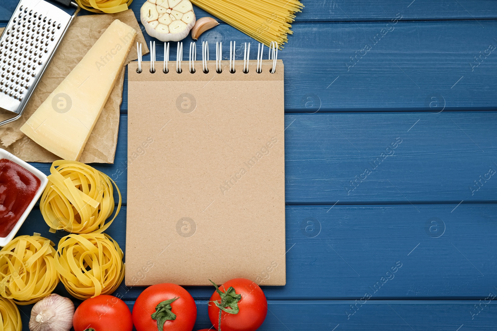 Photo of Blank recipe book and different ingredients on blue wooden table, flat lay. Space for text