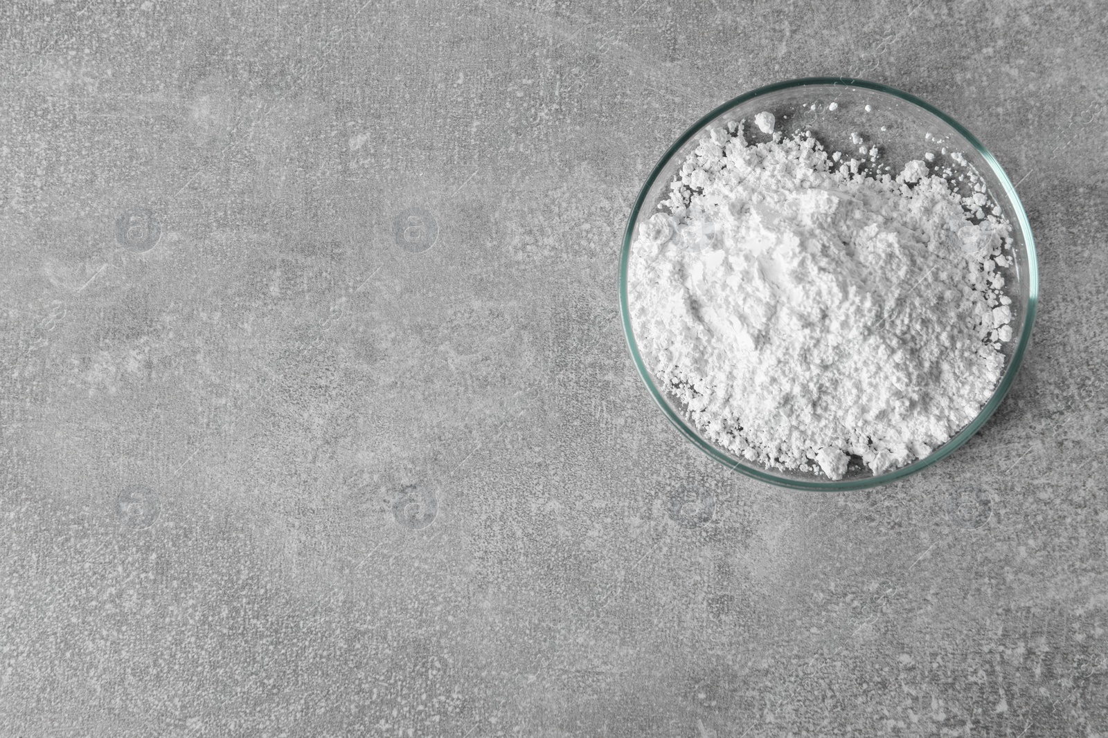 Photo of Petri dish with calcium carbonate powder on light grey table, top view. Space for text