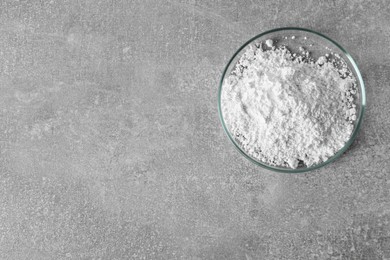 Petri dish with calcium carbonate powder on light grey table, top view. Space for text