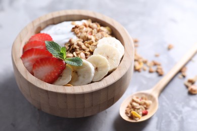 Photo of Tasty granola in bowl served on gray table, closeup