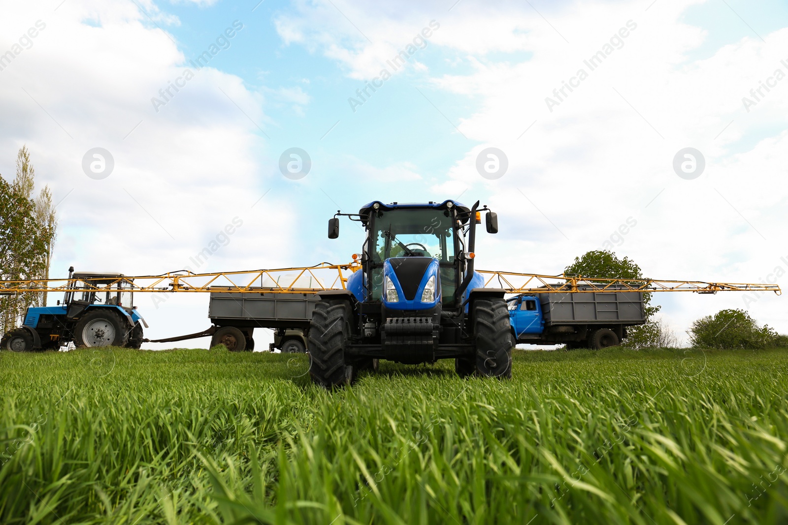 Photo of Tractors and truck in field on sunny day. Agricultural industry