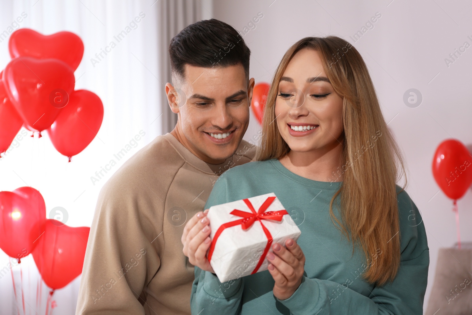 Photo of Lovely couple with gift in room. Valentine's day celebration