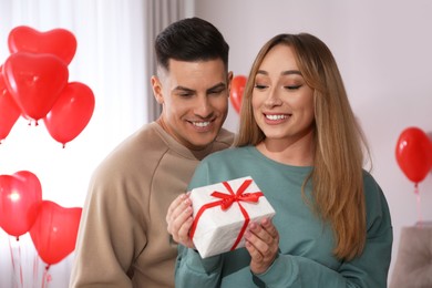 Photo of Lovely couple with gift in room. Valentine's day celebration