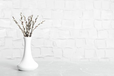 Photo of Beautiful pussy willow branches in vase on grey marble table, space for text