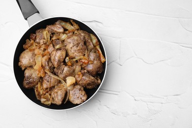 Pan with tasty fried chicken liver and onion on white textured table, top view. Space for text